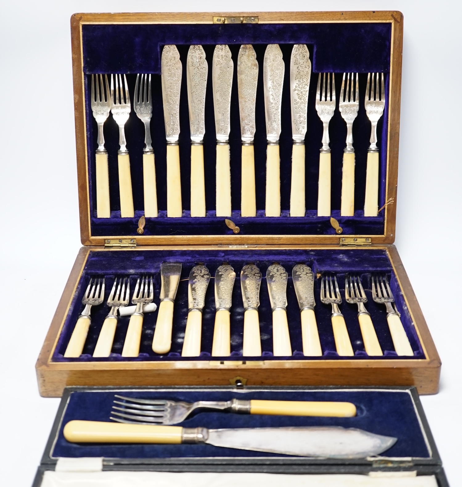 A set of twelve plated engraved fish knives and forks, with bone handles, cased together with a pair of plated fish servers with ivorine handles